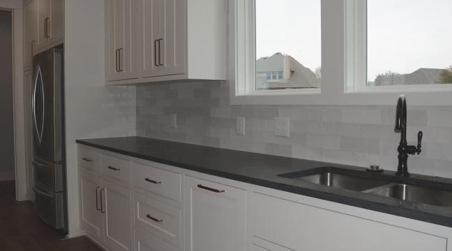 kitchen with white cabinets and black kitchen counter and sink by renovacraft