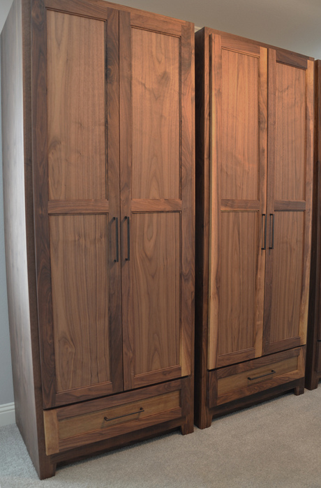 Two custom-made walnut wardrobes standing side by side against a wall.